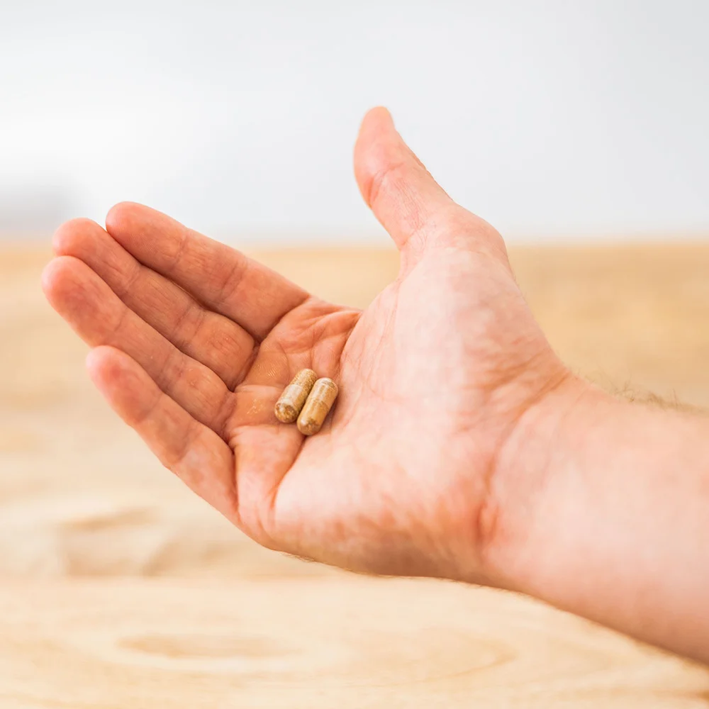 Two Active Move capsules resting in an open hand — the standard 2-capsule daily serving